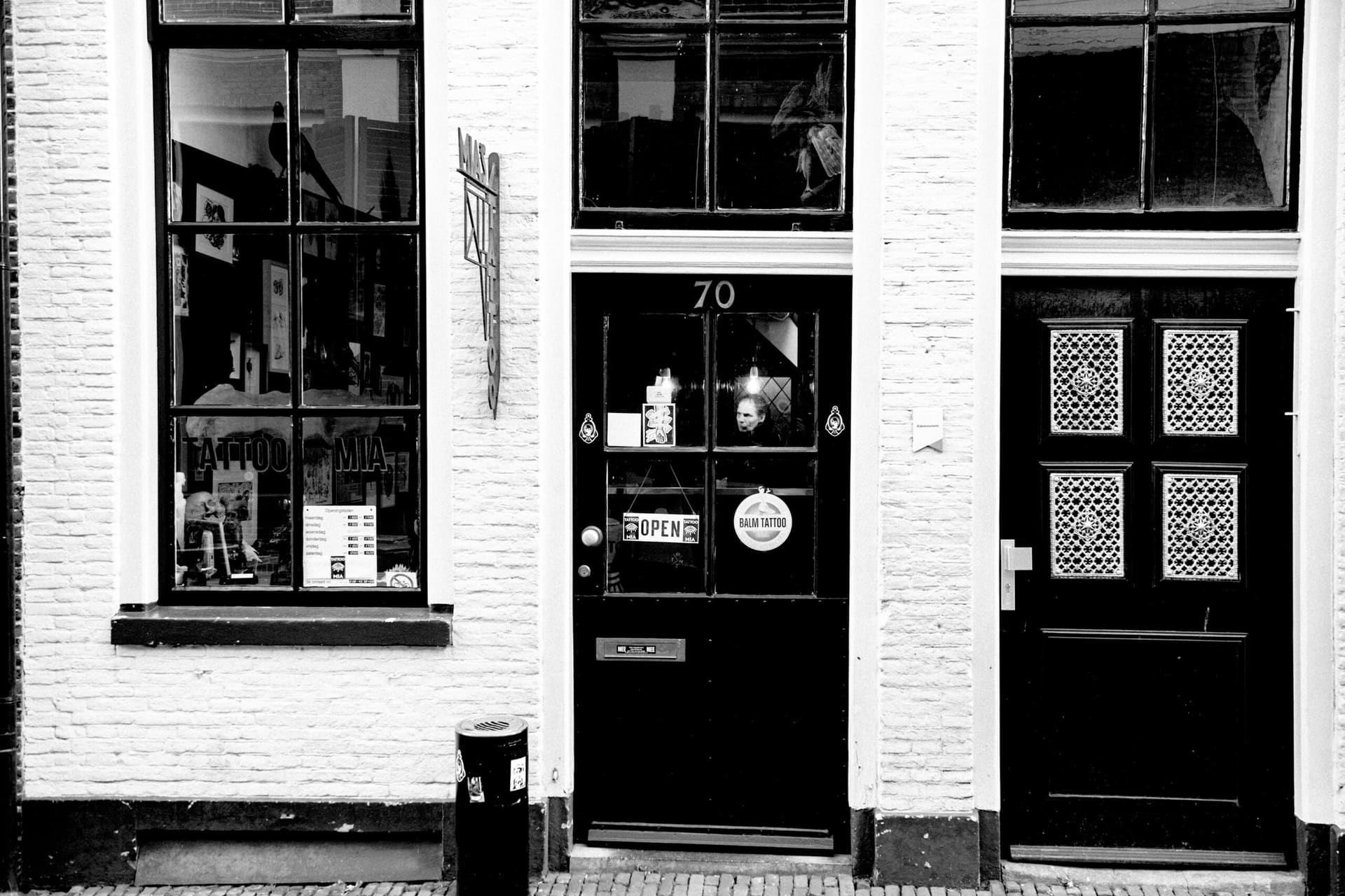 De gevel van Mia's Tattoo aan de Nieuwstraat in Zwolle: witte baksteen, een zwarte deur met huisnummer 70 en een bordje OPEN achter het glas.